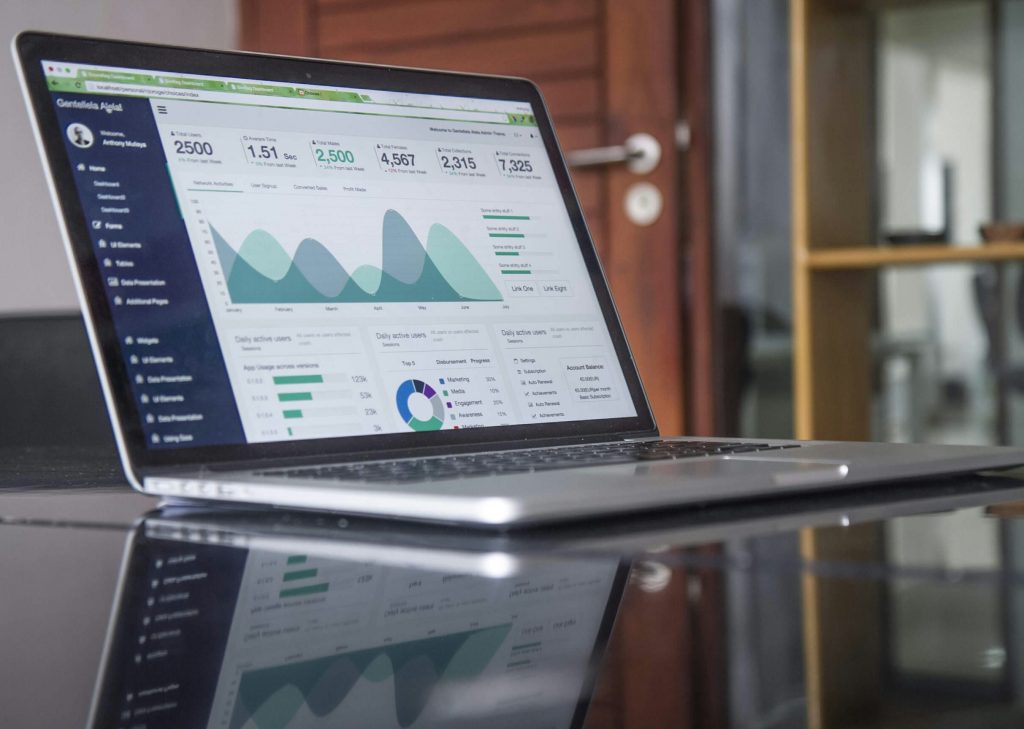 Laptop on a desk displaying a website analytics dashboard with charts and visitor metrics